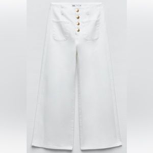 White flared cropped jeans with gold accent buttons